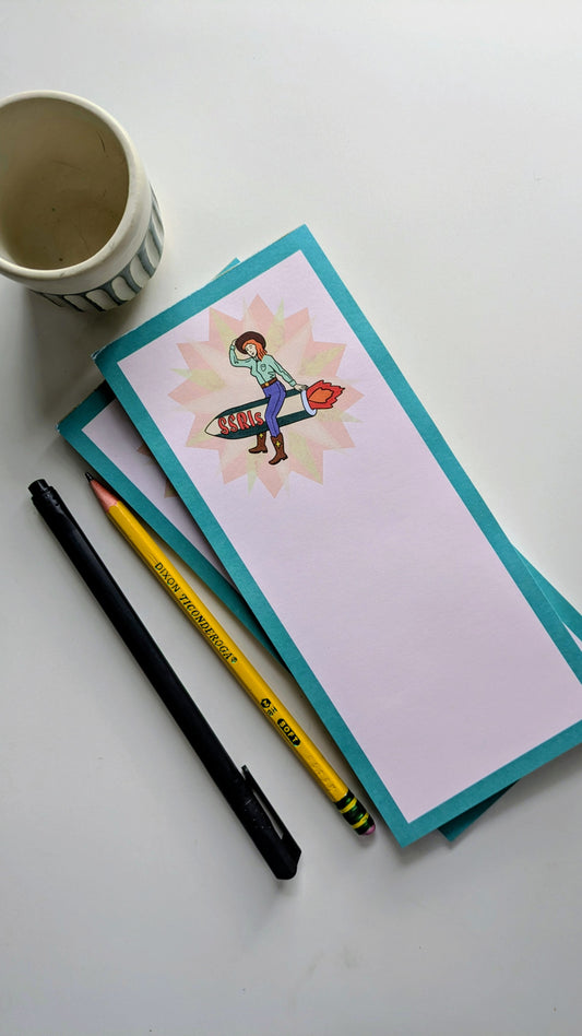 Notepad with a colorful illustration, pencil, and pen on a white surface