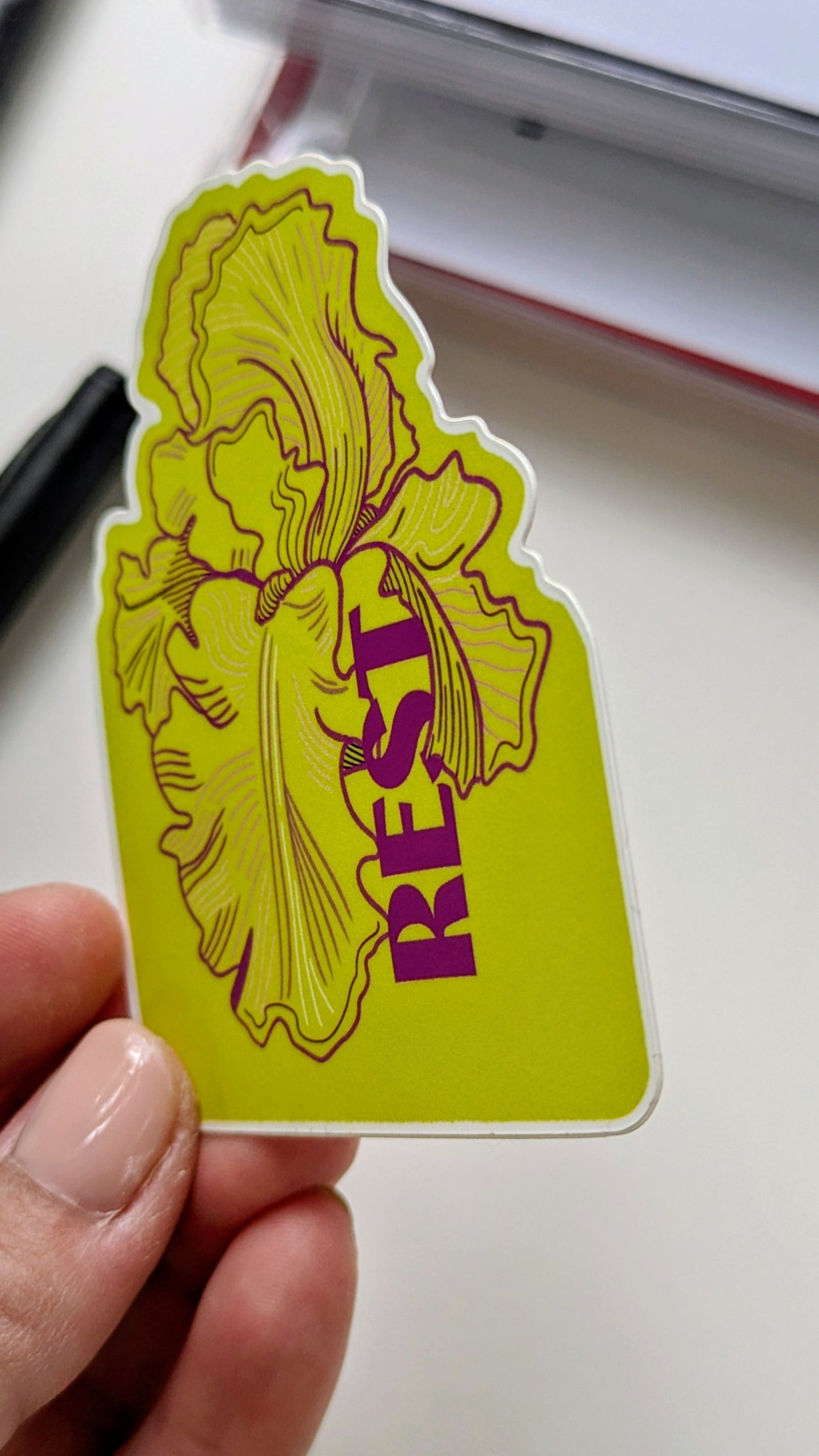 Nature illustration sticker featuring a bearded iris with the word "rest", held by a hand at an angle